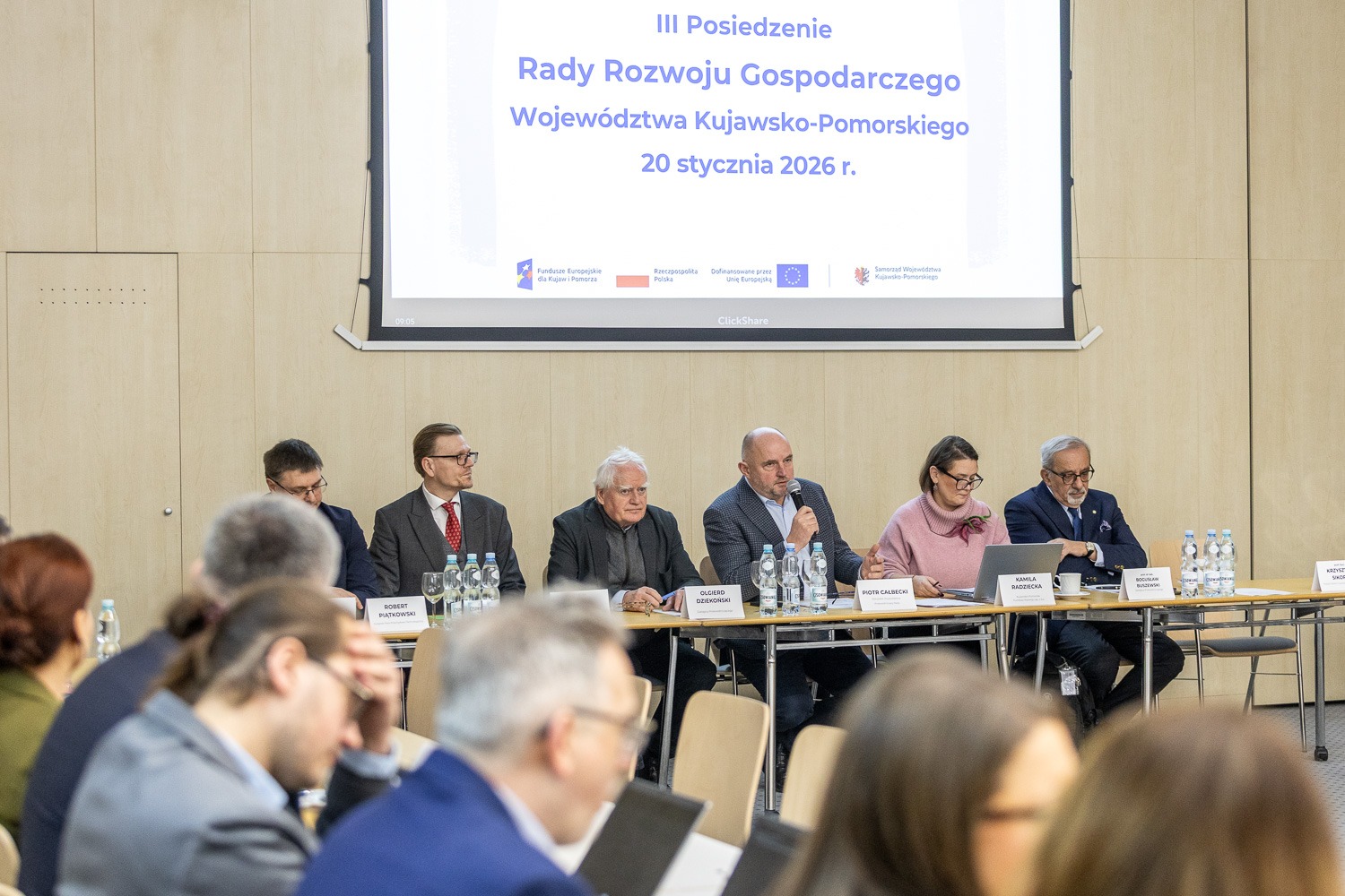 Widok na stół prezydialny podczas III Posiedzenia Rady Rozwoju Gospodarczego Województwa Kujawsko-Pomorskiego w dniu 20 stycznia 2026 r. Przy stole siedzą m.in. Robert Piątkowski, Olgierd Dziekoński, Piotr Całbecki i Kamila Radziecka.